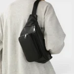 Sac Banane Homme Cuir Grainé Minimaliste Sac banane en cuir grainé noir porté en bandoulière dans le dos par un homme au style casual-chic