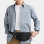 Sac Banane Homme Cuir Grainé Demi-Lune Sac banane en cuir grainé noir porté à la taille par un homme, de face au style casual chic