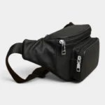 Sac Banane Homme Cuir Grainé Minimaliste Sac banane en cuir grainé noir posé de trois quarts, vue arrière avec plusieurs poches zippées argentées