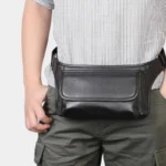 Sac banane cuir motard noir porté à la taille par un homme, vue rapprochée de face