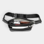 Sac banane cuir motard noir ouvert vu de dessus, laissant voir plusieurs essentiels du quotidien rangés