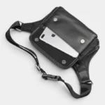 Sac banane cuir motard noir avec poche avant ouverte laissant apparaître un téléphone, vue rapprochée