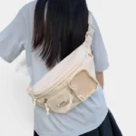 Sac banane femme en nylon beige porté en bandoulière dans le dos par une femme au style casual-chic
