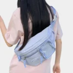 Grand sac banane femme en nylon bleu pastel porté en bandoulière dans le dos par une femme, vue de dos