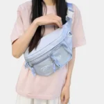 Grand sac banane femme en nylon bleu pastel porté en bandoulière croisée par une femme au style kawaii