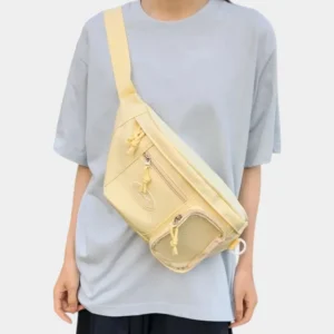 Grand sac banane femme en nylon jaune pastel porté en bandoulière croisée par une femme au style streetwear décontracté