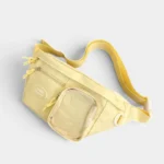 Grand sac banane femme en nylon jaune pastel, posé de face avec une poche mesh transparente