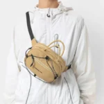 Sac Banane Technique Gorpcore Outdoor Nylon Ripstop Sac banane nylon beige porté en bandoulière croisée de face par une personne au style gorpcore outdoor