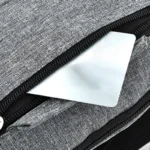 Sac banane gris en nylon, gros plan sur la poche avant ouverte avec une carte glissée à l'intérieur