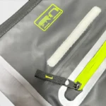 Sac banane moto en PVC gris, gros plan sur le velcro et la tirette jaune fluo de la fermeture éclair