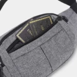 Sac banane en nylon gris, gros plan sur la poche principale ouverte révélant deux cartes bancaires noires et dorées