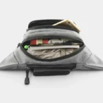 Sac banane en nylon gris vu de dessus, poche principale ouverte révélant des stylos et un téléphone