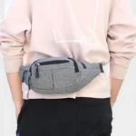 Sac banane en nylon gris porté à la taille de face par une personne au style streetwear décontracté