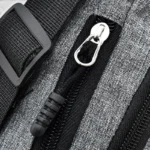 Sac banane en nylon gris, gros plan sur la tirette argentée et le zip noir de la fermeture éclair latérale