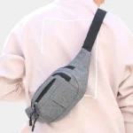 Sac banane en nylon gris porté en bandoulière croisée dans le dos par une personne au style casual-chic