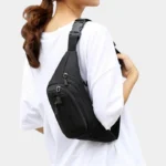 Sac banane en nylon noir porté en bandoulière croisée dans le dos par une femme au style décontracté