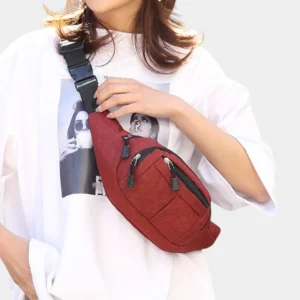 Sac banane en nylon rouge porté en bandoulière croisée par une femme au style casual-chic oversize, vue de face