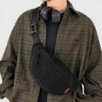 Sac banane nylon noir porté en bandoulière croisée par un homme au style streetwear décontracté