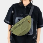 Sac banane nylon froissé vert kaki porté en bandoulière croisée par une femme au style streetwear urbain-décontracté