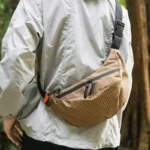 Grand Sac Banane Nylon Ripstop Quadrillé Imperméable Sac banane nylon quadrillé beige porté en bandoulière par un homme au style outdoor-casual