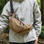 Grand Sac Banane Nylon Ripstop Quadrillé Imperméable Sac banane nylon quadrillé beige porté en bandoulière par un homme, de face, au style outdoor