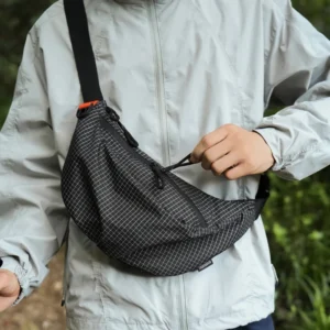 Sac banane nylon quadrillé noir porté en bandoulière de face par un randonneur au style outdoor