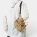 Sac Banane Technique Gorpcore Outdoor Nylon Ripstop Sac banane nylon beige porté en bandoulière dans le dos par une silhouette au style gorpcore outdoor