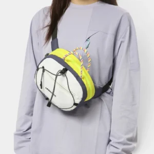 Sac banane nylon bicolore blanc et jaune fluo porté en bandoulière par une femme, de face au style gorpcore