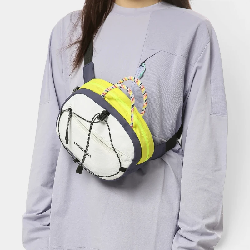 Sac banane nylon bicolore blanc et jaune fluo porté en bandoulière par une femme, de face au style gorpcore