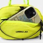Sac Banane Technique Gorpcore Outdoor Nylon Ripstop Sac banane nylon jaune fluo, poche avant ouverte sur un smartphone en gros plan