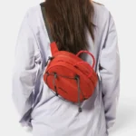 Sac Banane Technique Gorpcore Outdoor Nylon Ripstop Sac banane nylon rouge porté en bandoulière dans le dos par une femme, vue de dos