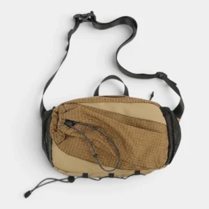 Sac banane randonnée en nylon beige chaud posé à plat de face, avec poche avant texturée quadrillée et filets latéraux
