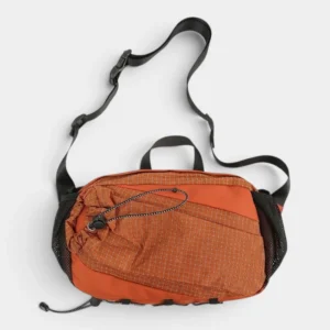 Sac banane randonnée en nylon orange rouille posé à plat de face, avec sangle réglable noire à clip plastique