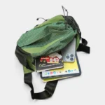 Grand sac banane randonnée en nylon ripstop vert, vu de dessus avec la poche principale ouverte révélant une tablette et un smartphone