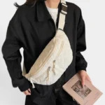 Grand Sac Banane Femme Velours Côtelé Matelassé Sac banane en velours côtelé beige porté en bandoulière croisée par une femme au style streetwear décontracté