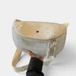 Grand Sac Banane Femme Velours Côtelé Demi-Lune Sac banane en velours côtelé beige crème de forme demi-lune, tenu à la main de face avec une sangle réglable