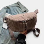 Grand Sac Banane Femme Velours Côtelé Demi-Lune Sac banane en velours côtelé taupe demi-lune tenu à la main, présenté de face avec sa double tirette argentée