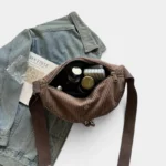 Grand Sac Banane Femme Velours Côtelé Demi-Lune Sac banane en velours côtelé marron, poche principale ouverte révélant un flacon de parfum et ses essentiels