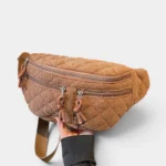 Grand Sac Banane Femme Velours Côtelé Matelassé Grand sac banane en velours côtelé matelassé camel, tenu à la main et présenté de face avec une sangle à motif bicolore