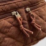 Grand Sac Banane Femme Velours Côtelé Matelassé Gros plan sur les tirettes zippées d'un sac banane en velours côtelé matelassé marron, avec des cordons noués assortis