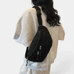 Grand Sac Banane Femme Velours Côtelé Matelassé Grand sac banane en velours côtelé matelassé noir porté en bandoulière de dos par une femme au style sport-chic