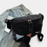 Grand Sac Banane Femme Velours Côtelé Demi-Lune Sac banane velours côtelé noir demi-lune posé de face, avec une sangle réglable et des tirettes tressées
