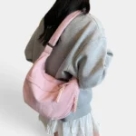 Sac Banane XXL Femme Velours Côtelé Sac banane XXL en velours côtelé rose poudré porté en bandoulière par une femme, de dos au style casual-chic