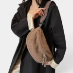 Grand Sac Banane Femme Velours Côtelé Demi-Lune Sac banane en velours côtelé taupe porté en bandoulière par une femme au style chic décontracté