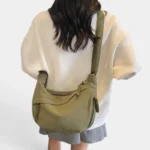 Sac Banane XXL Femme Velours Côtelé Sac banane XXL en velours côtelé vert kaki porté en bandoulière dans le dos par une femme au style casual-chic