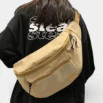 Grand Sac Banane XXL Streetwear Sac banane XXL nylon beige porté en bandoulière dans le dos par une femme au style streetwear