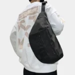 Grand Sac Banane XXL Streetwear Grand sac banane XXL en nylon noir porté en bandoulière par un homme de dos au style streetwear