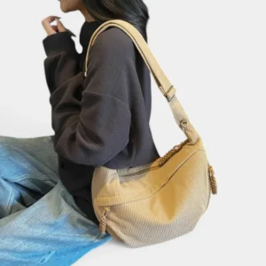 Sac banane XXL en velours côtelé beige porté sur l'épaule par une femme au style casual chic