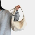 Sac Banane XXL Femme Velours Côtelé Sac banane XXL en velours côtelé beige porté à la main par une femme au style casual chic