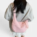 Sac Banane XXL Femme Velours Côtelé Sac banane XXL en velours côtelé rose poudre porté en bandoulière par une femme, vue de dos au style casual chic
